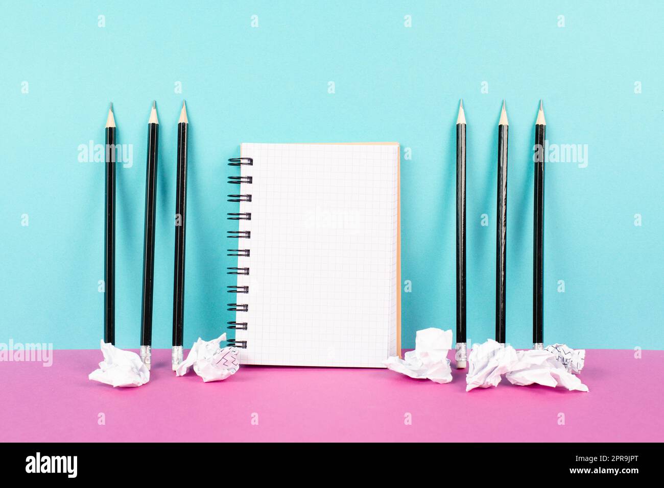 Notebook with copy space, pencils and crumpled up paper on a pink and blue background, brainstorming for new ideas, writing a message, home office desk Stock Photo