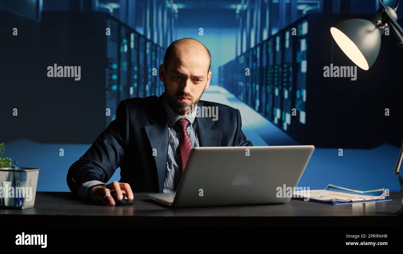 Data center technician feeling tired working in server room, doing cloud computing digitalization for database storage. Man engineer inspecting computer system and hardware, IT industry. Stock Photo