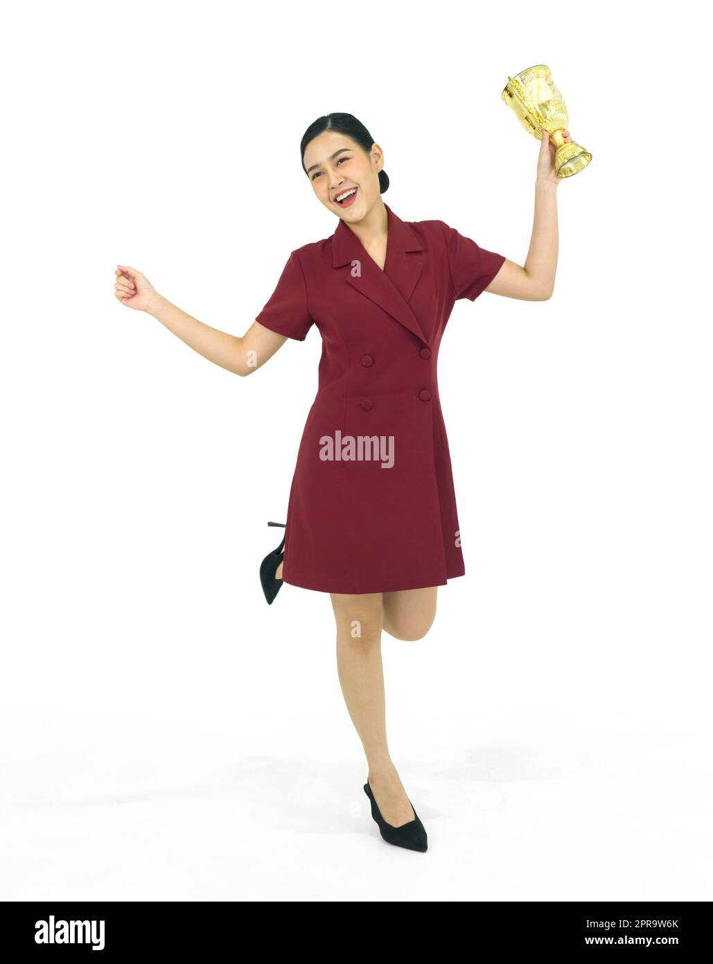 Asian businesswoman in red dress holding the golden trophy while stand in one leg. Portrait on white background with studio light. Stock Photo