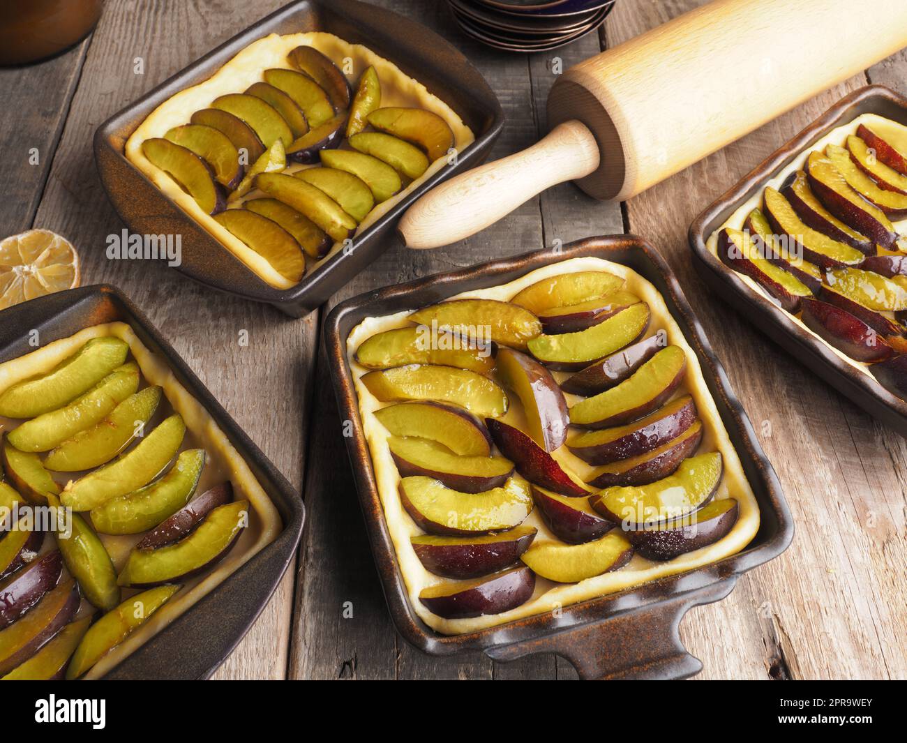Plum cake prepared for baking on a rustic wooden kitchen table Stock Photo