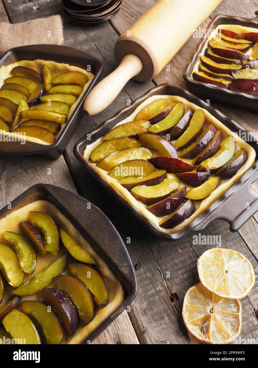 Plum cake prepared for baking on a rustic wooden kitchen table Stock Photo