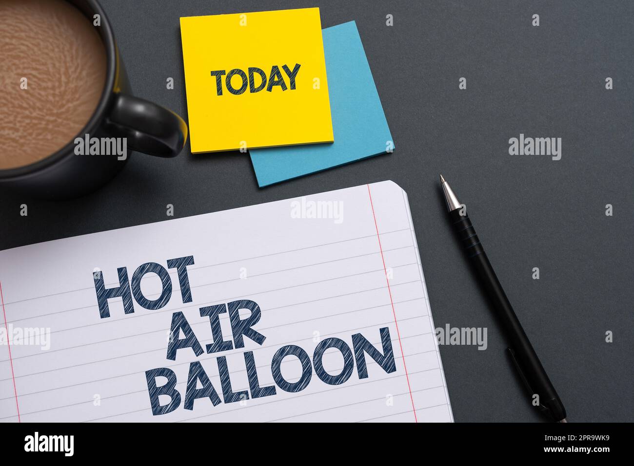 Text sign showing Hot Air Balloon. Concept meaning Have a ride in the inside a basket flight romantic trip Notebook With Important Message On Desk With Coffee, Pen And Notes. Stock Photo