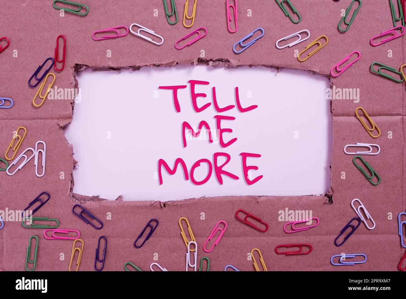 Text sign showing Tell Me More. Business approach A call to start a conversation Sharing more knowledge Important Ideas Written Under Ripped Cardboard With Paperclips Around. Stock Photo