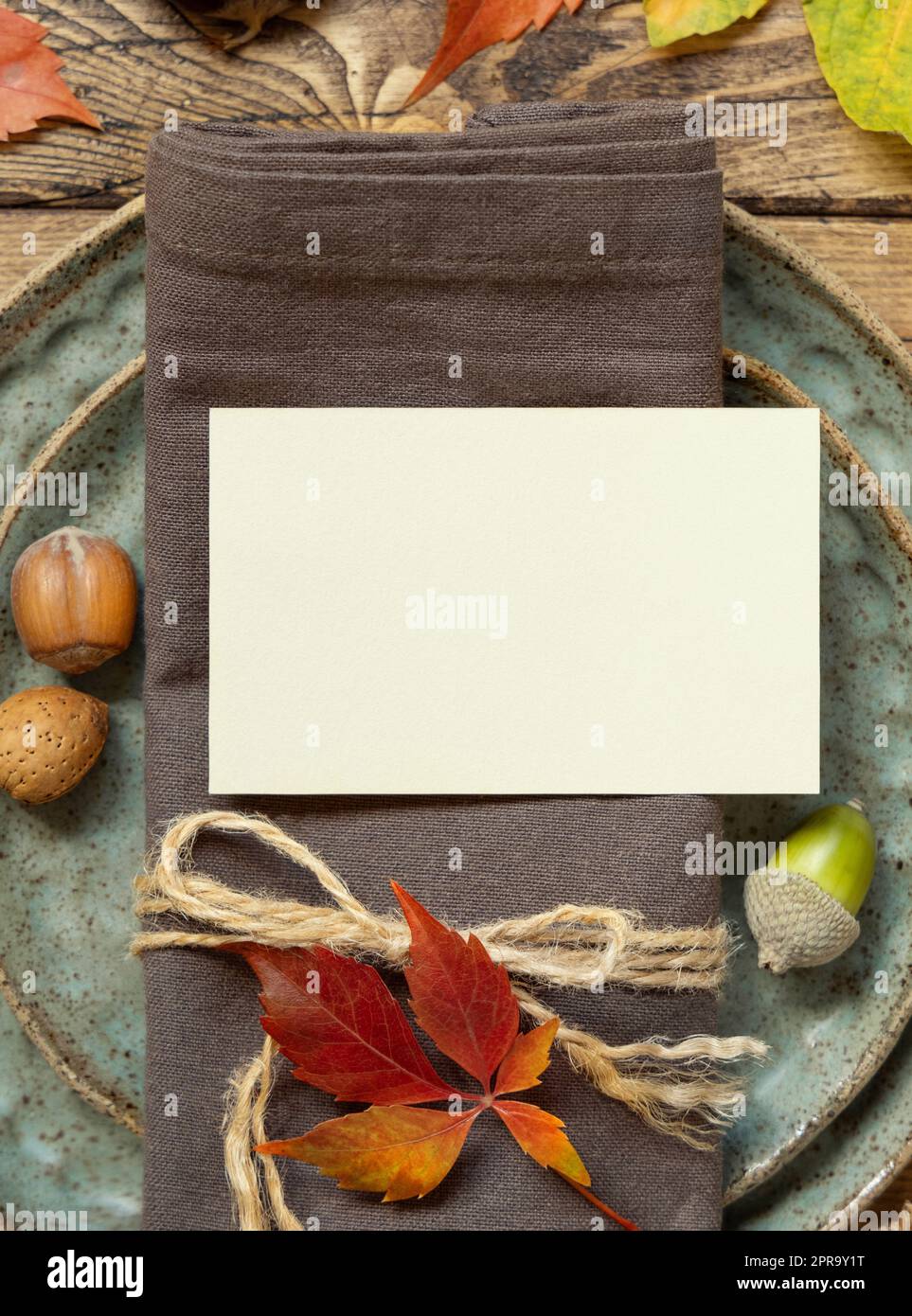 Autumn rustic table setting with blank place card between colorful leaves and berries top view, mockup Stock Photo