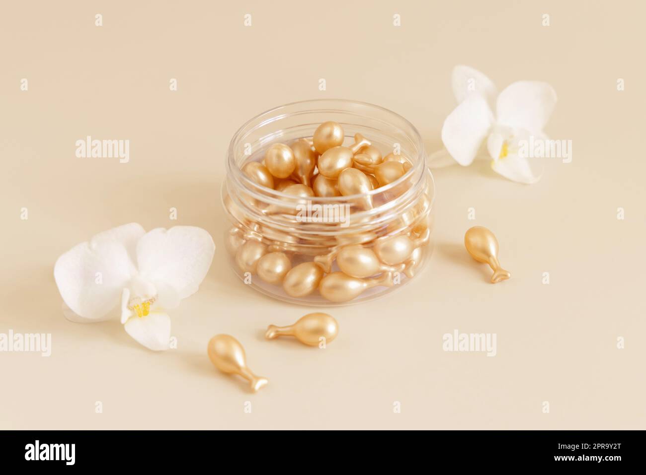 Face serum capsules in a jar near orchid flowers on light yellow close up. Beauty product Stock