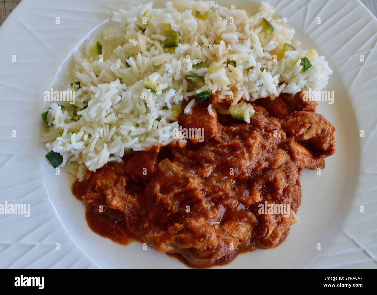 Butter chicken with basmati rice on a white plate Stock Photo