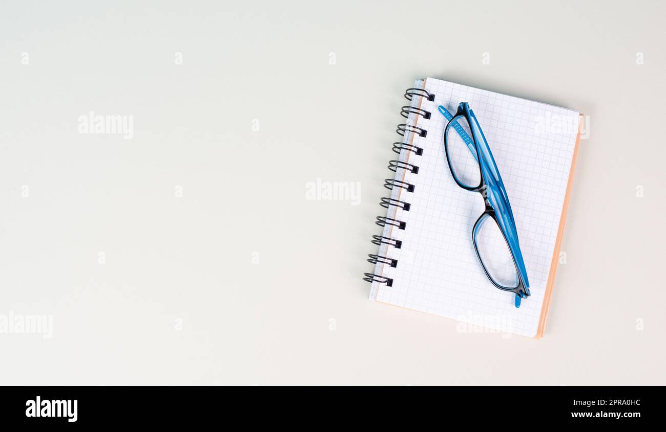 Empty notebook and eyeglasses on a gray background, brainstorming for new ideas, writing a message, home office desk, template of a workspace, copy space for text Stock Photo