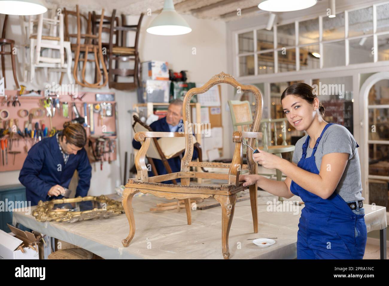 Professional craftswoman restorer in uniform renewing oldfashioned