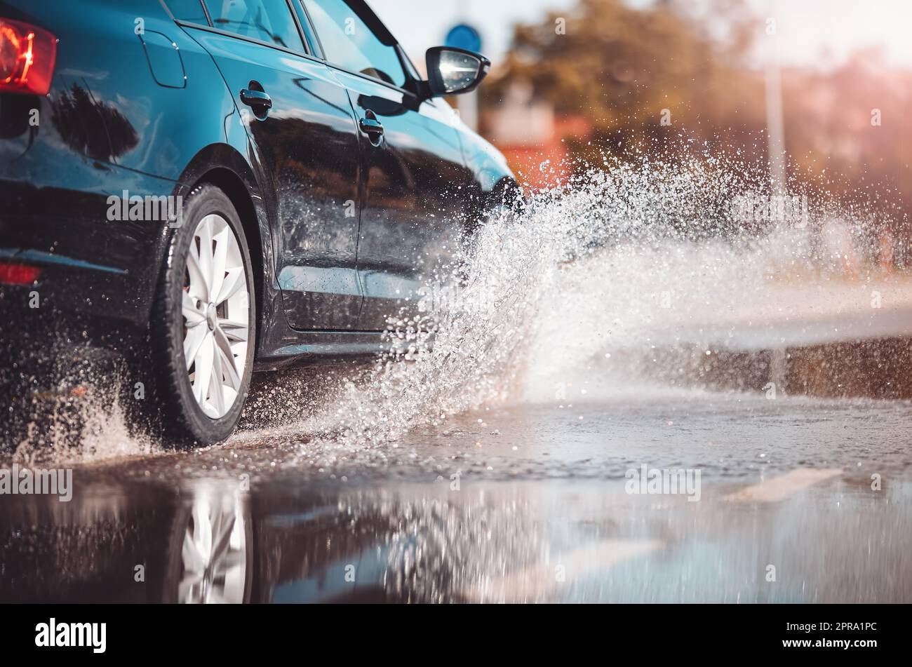 Car driving through the puddle and splashing by water. Dangerous
