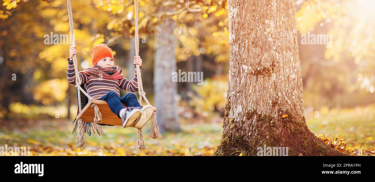 Happy girl sitting on the swing in autumn natural park Stock Photo