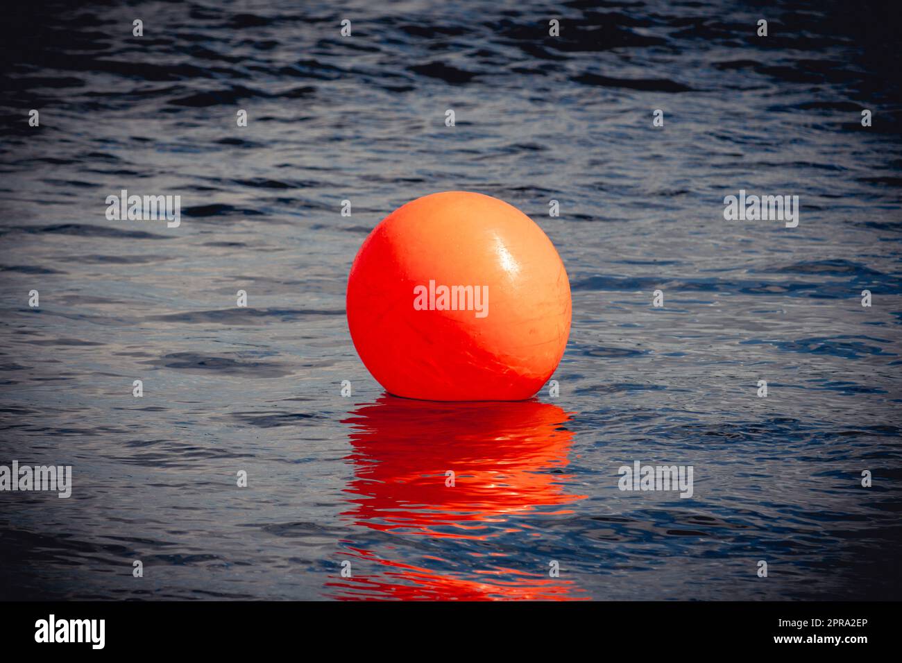 Orange buoy floating on dark dramatic sea water Stock Photo