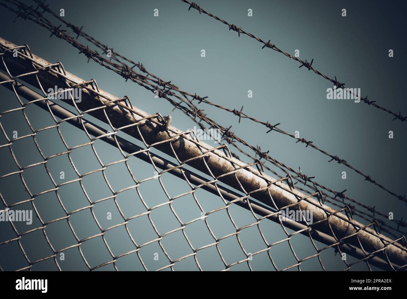 Barbed wire fence against dramatic, dark sky Stock Photo
