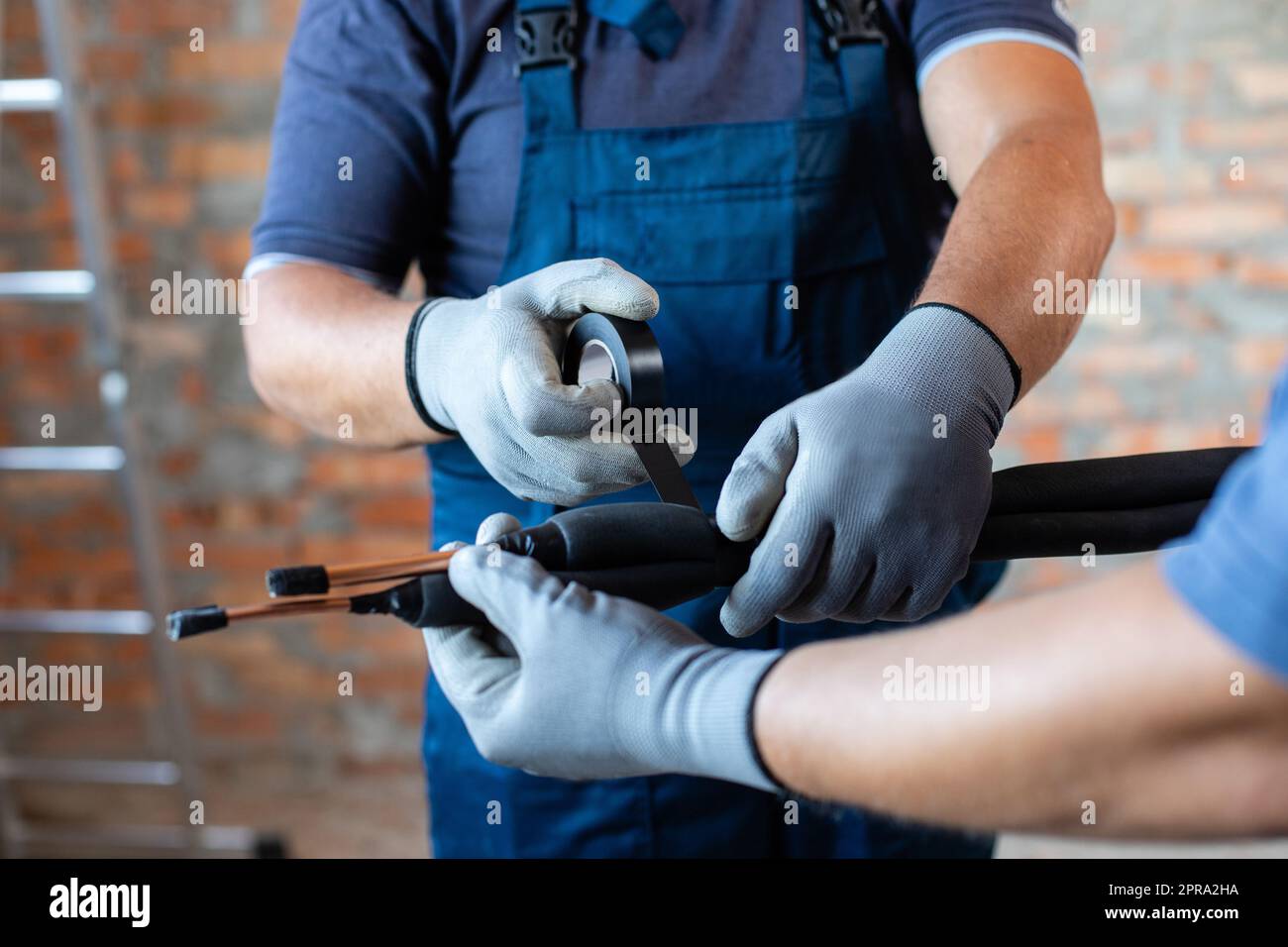 Two adult male workers in overalls are preparing to install underfloor heating pipes. Stock Photo