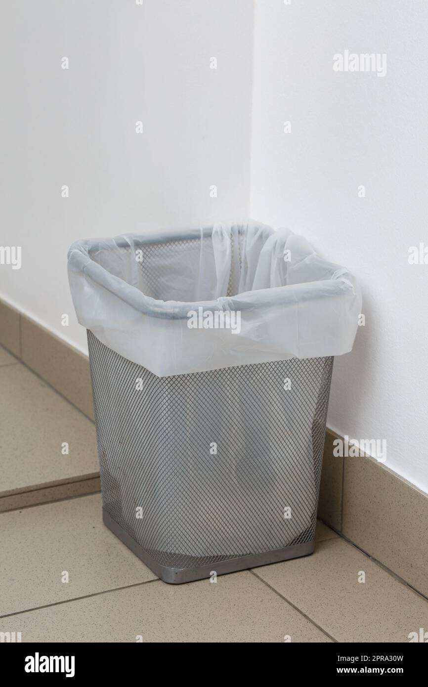 Close up of metal gray trash can with white garbage bag inside. Stock Photo