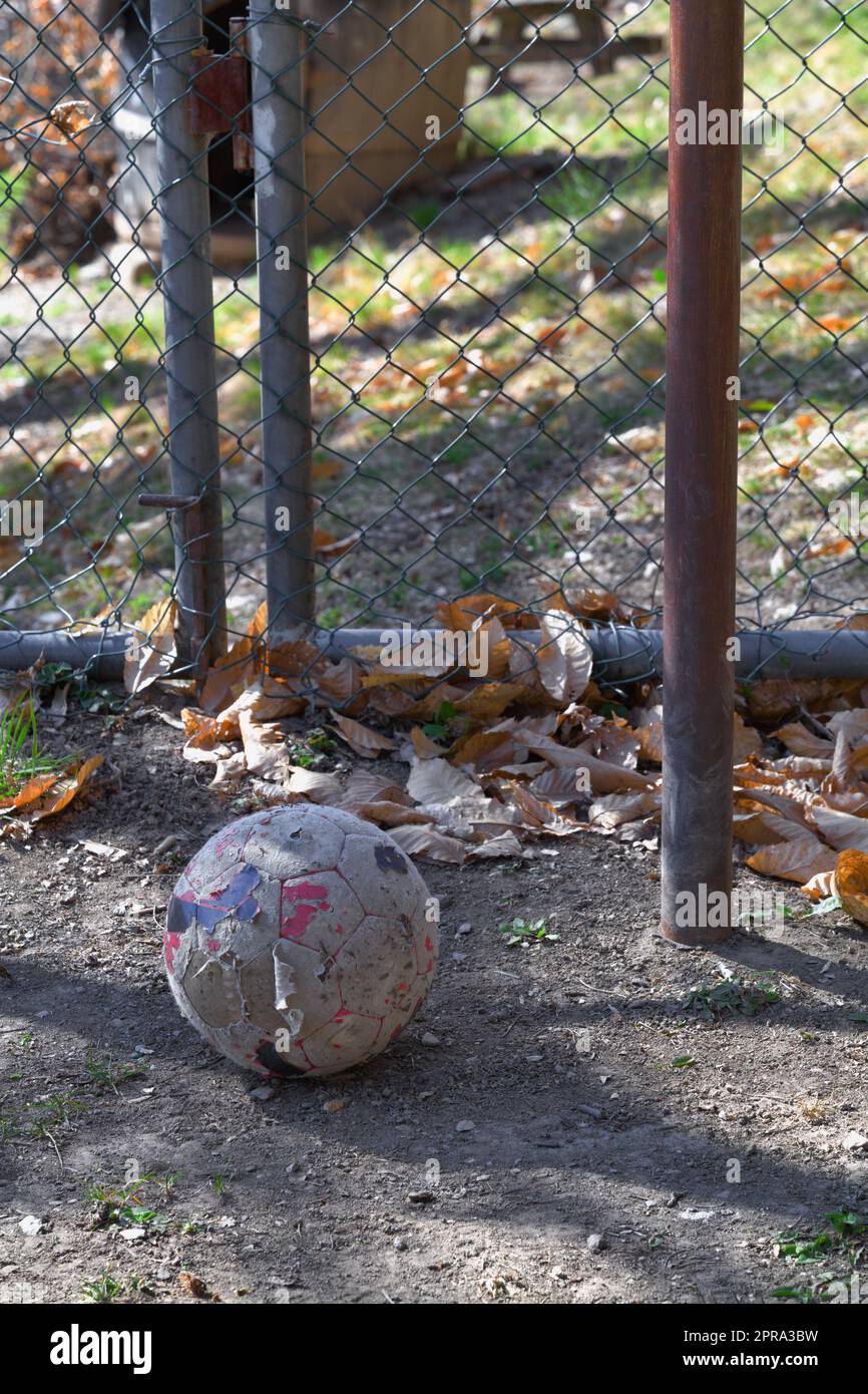 Old dirty football lying on the abandoned playground. Parts of the old