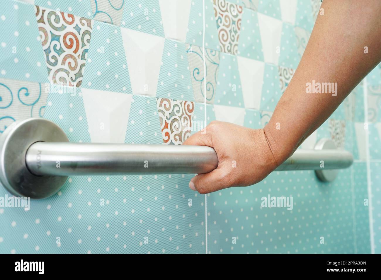 Asian woman patient use toilet support rail in bathroom, handrail safety grab bar, security in nursing hospital. Stock Photo