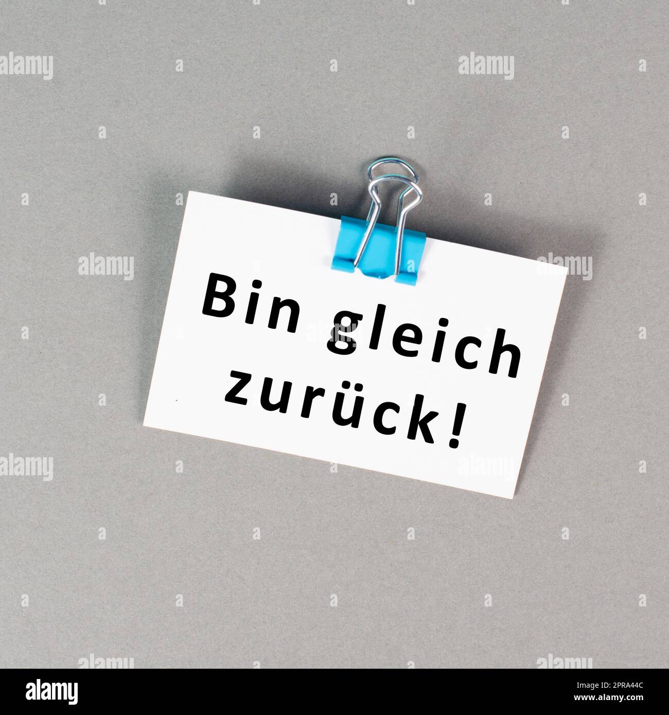 I will be back soon is standing in german language on a paper, taking a break, leaving a message on the desk Stock Photo