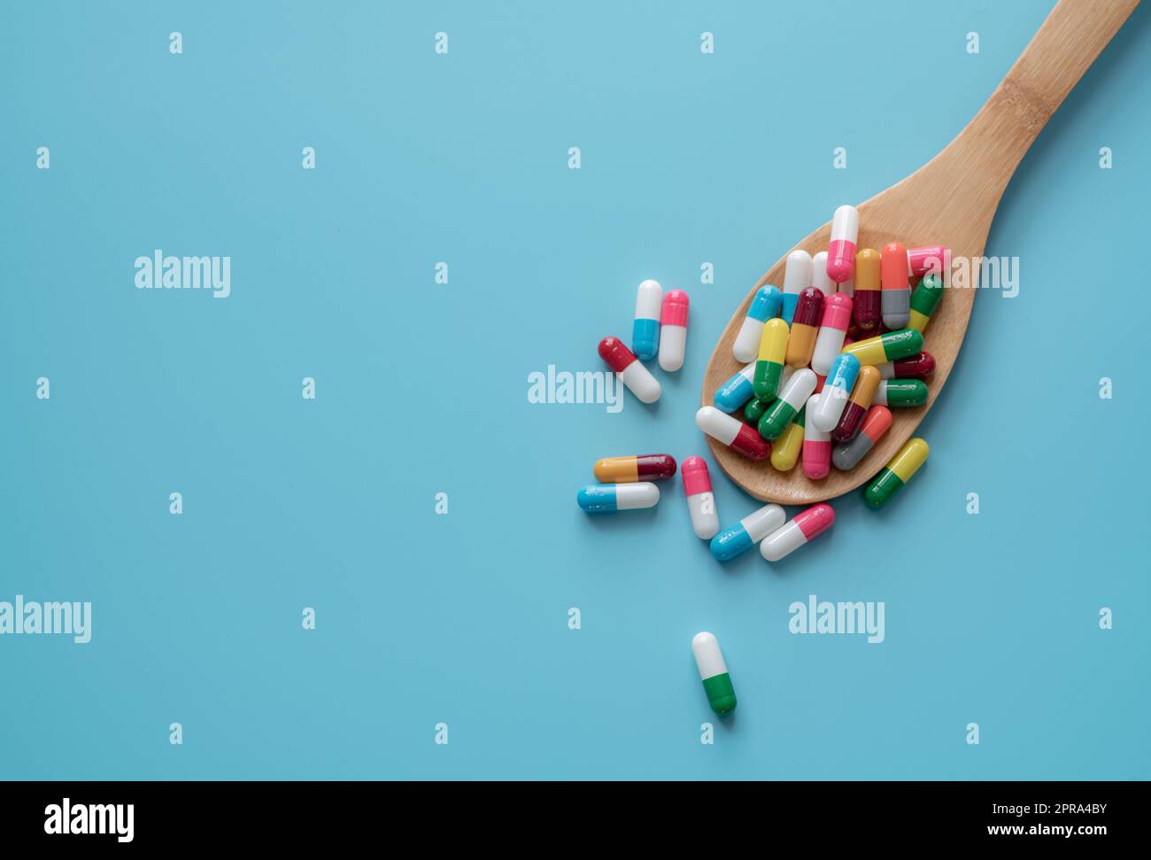 Antibiotic capsule pills on spoon and blue background. Antibiotic drug resistance. Pharmaceutics. Medical health care. Prescription drugs. Drug use problems. Dose of medicine. Pharmaceutical care. Stock Photo