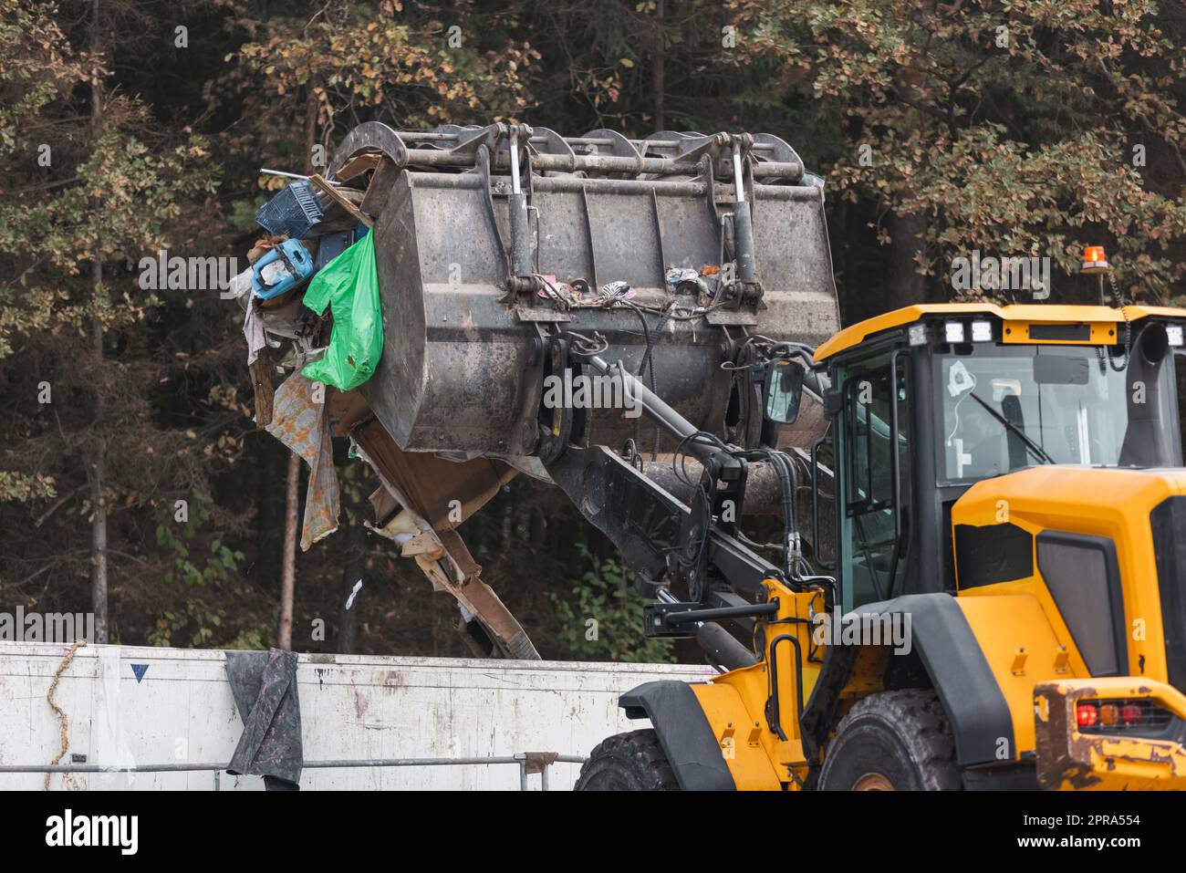 Waste loading operation, loader dumping trash in a truck on a site for