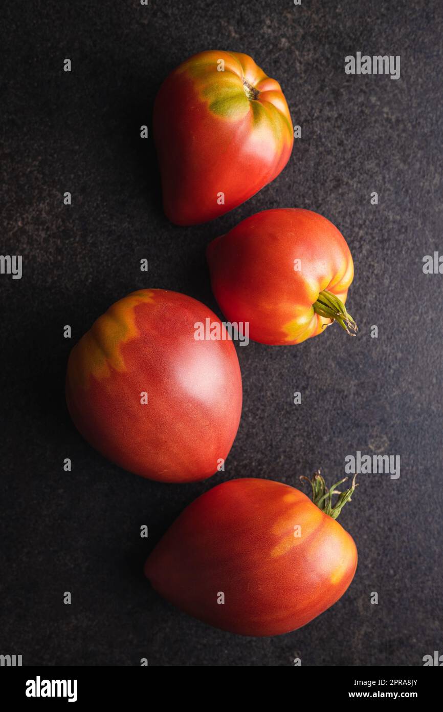 Bull heart tomatoes on black table. Stock Photo