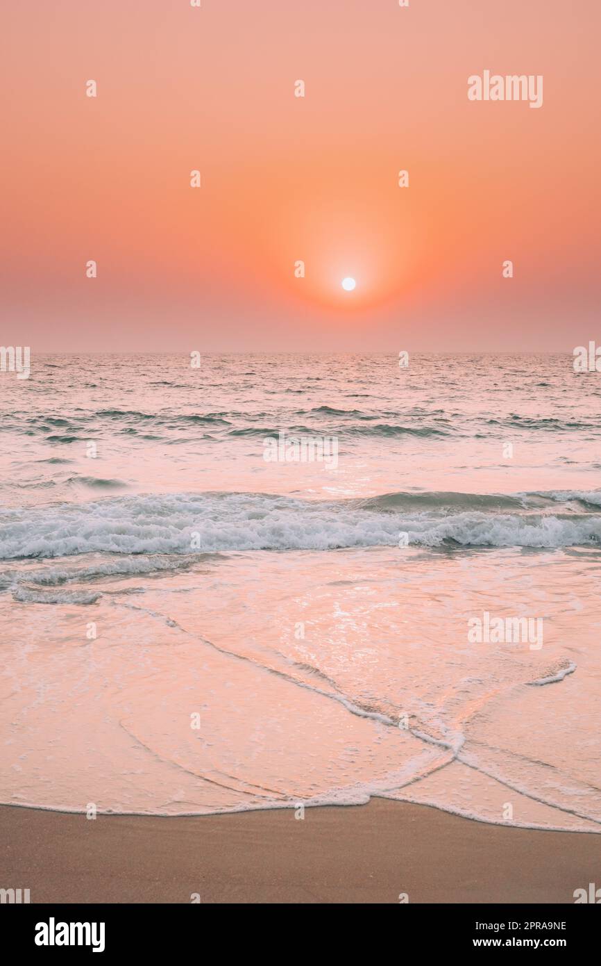 Sunset Sun Shine Above Sea. Natural Sunrise Sky Warm Colors Over Ripple Sea. Ocean Water Foam Splashes Washing Sandy Beach Stock Photo
