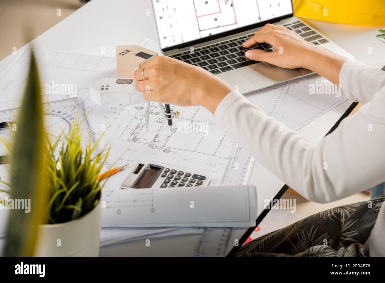 Architect typing laptop keyboard to review design of house before editing with compass Stock Photo
