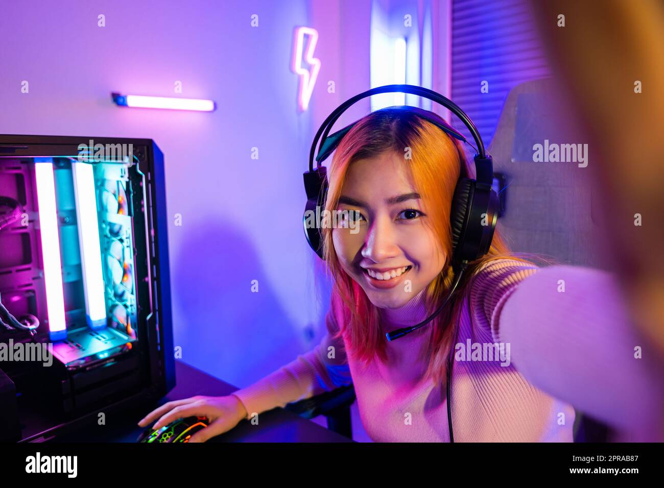 Happy gamer recording and saying hello her fans during live streaming before playing video game online Stock Photo