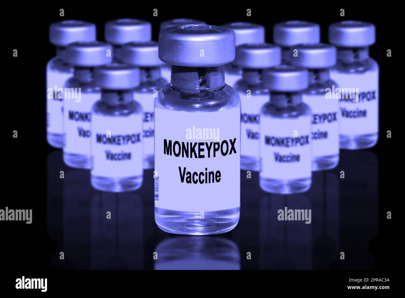Monkeypox vaccine close-up on a black mirror background. In the background are blurred vaccine vials Stock Photo