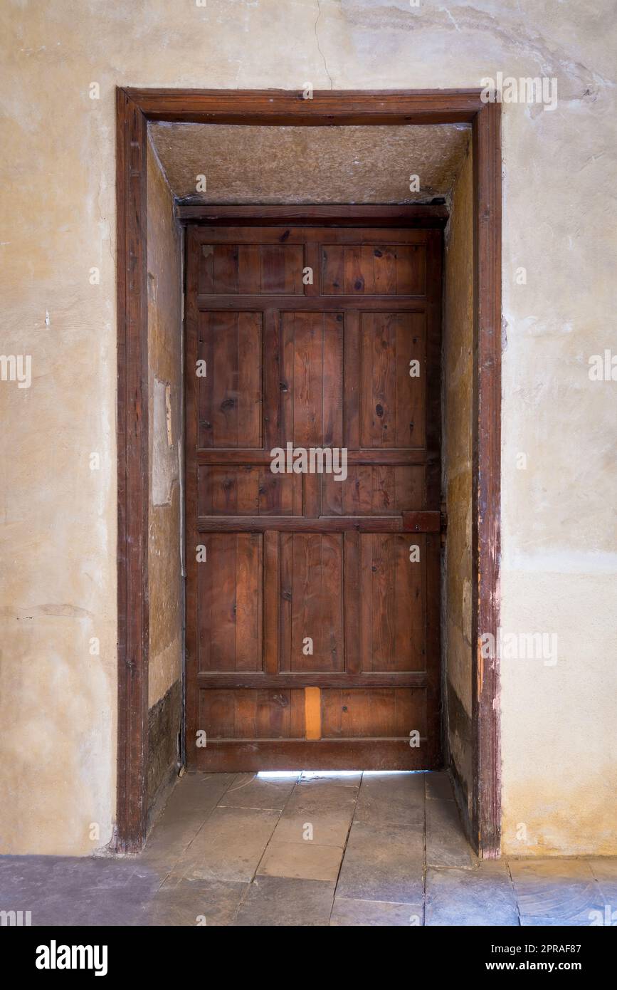 Recessed grunge wooden aged closed door on grunge stone wall Stock Photo