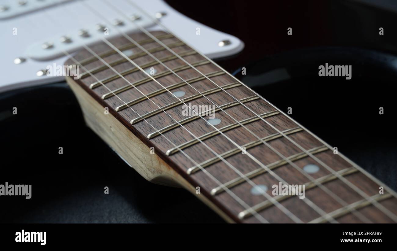 Guitar neck of black electric guitar on dark background Stock Photo