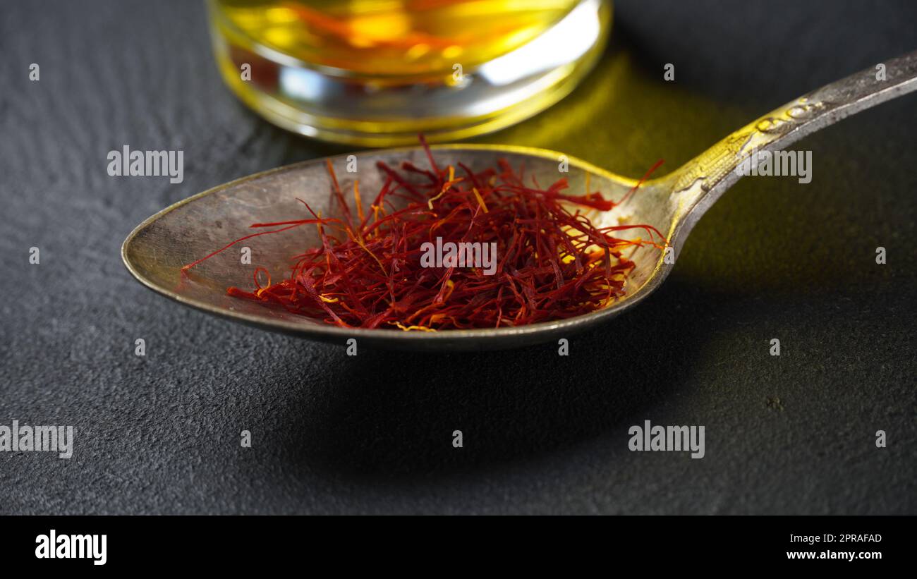 Expensive Red Dried saffron spice in a spoon on dark background Stock Photo