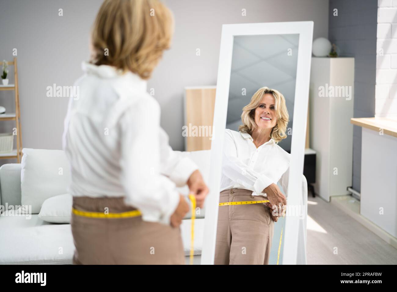 Smiling Slim Woman Looking At Her Reflection Stock Photo