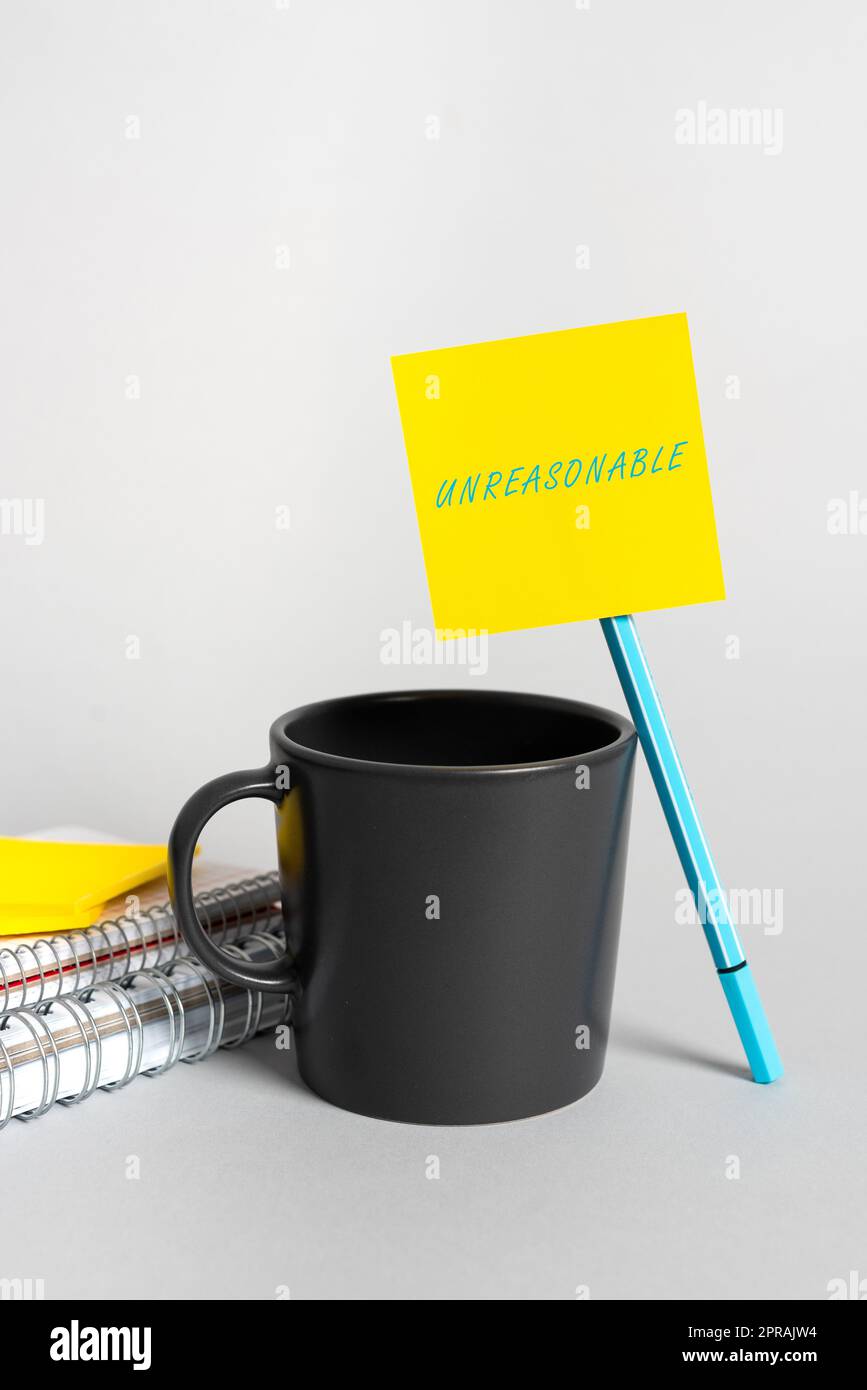 Conceptual display Unreasonable. Word for Beyond the limits of acceptability or fairness Inappropriate Cup, Pen, Notebooks And Sticky Note With Important Announcement On Desk. Stock Photo