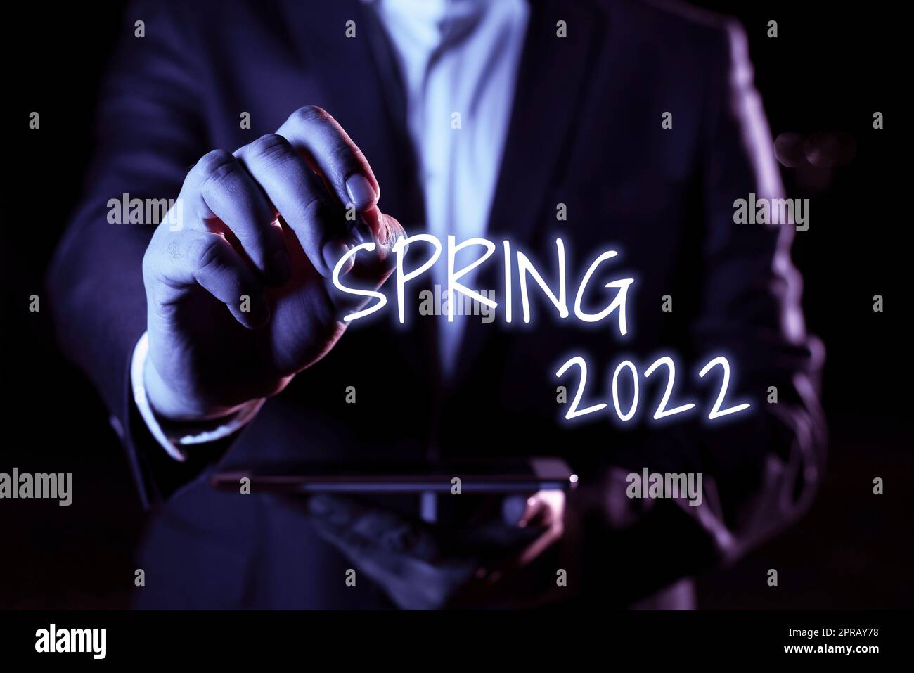 Conceptual caption Spring 2022. Business overview time of year where flowers rise following winter season Hand With Pen Pointing Important Infortmations With Other Holding Tablet Stock Photo