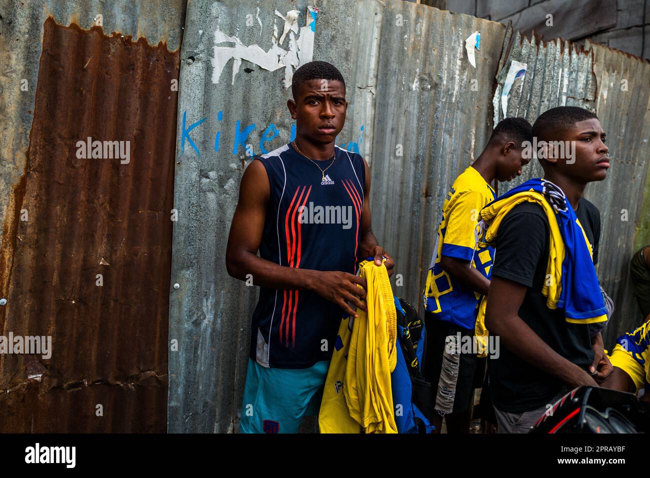 Young Afro-Colombian football players wear their jerseys outside, next to the dirt playing field, before playing a match in Quibdó, Chocó, Colombia. Stock Photo