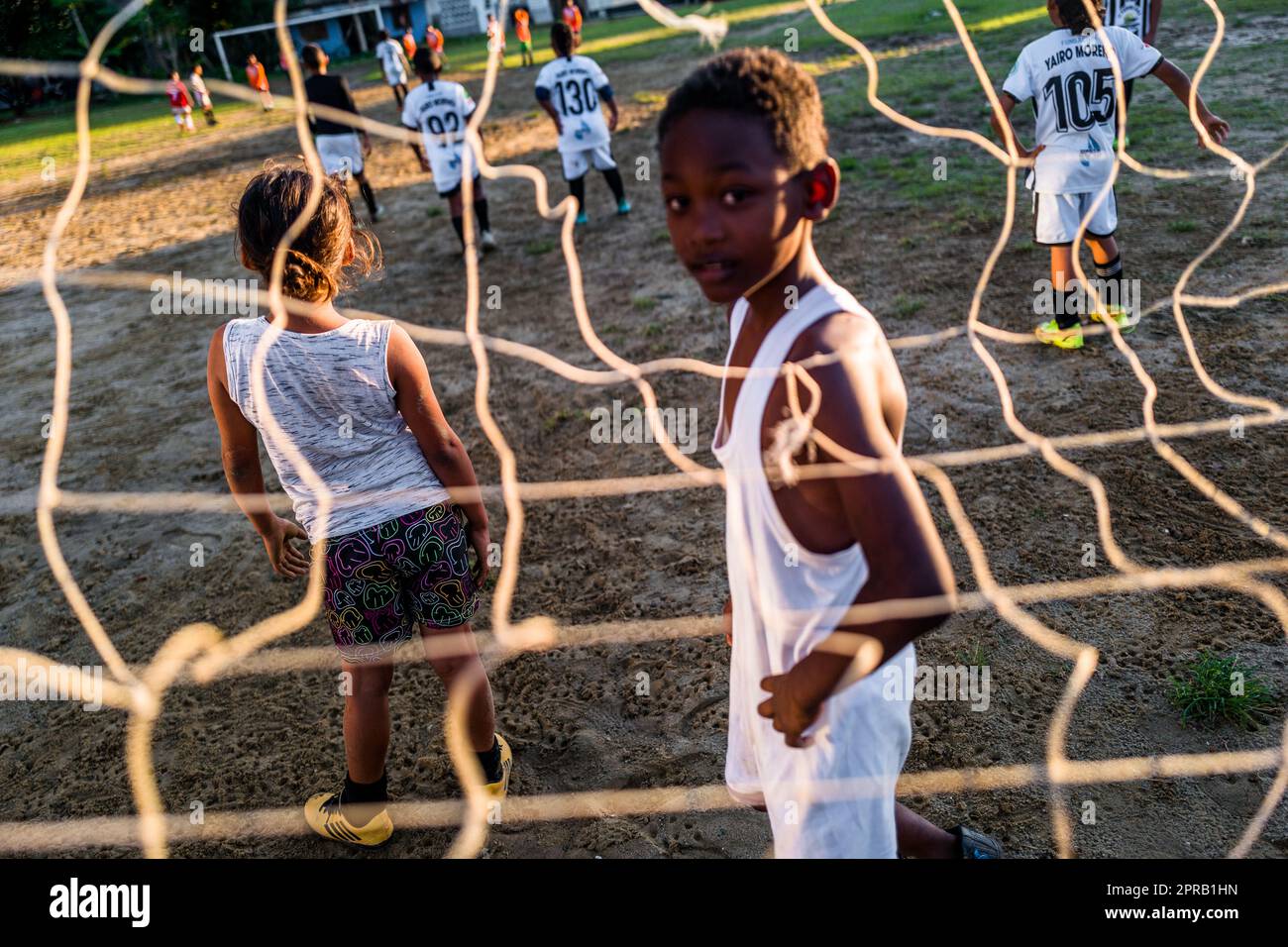 Young Afro-Colombian football players play a friendly match during a training session on a dirt playing field in Necoclí, Antioquia, Colombia. Stock Photo