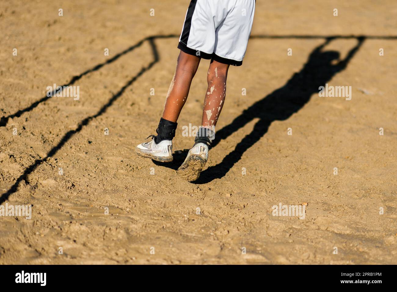 A young Afro-Colombian football player swings on the crossbar of a goal during a training session in Necoclí, Antioquia, Colombia. Stock Photo