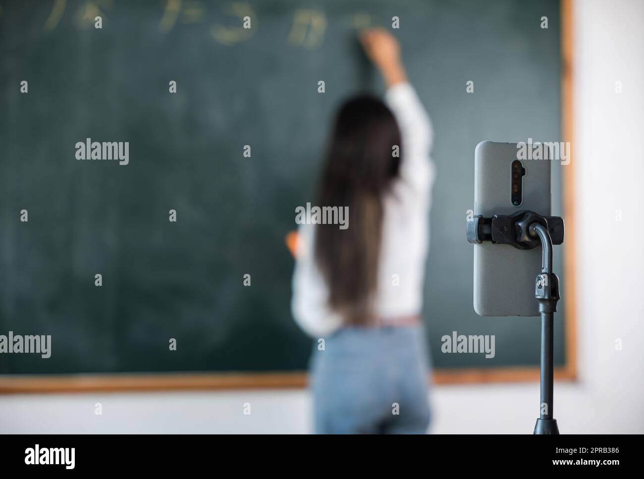 Asian teacher teach on board while have blackboard lecture online through smartphone in classroom Stock Photo