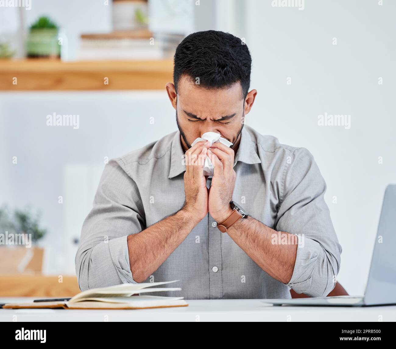 I think I feel a cold coming on. a young businessman blowing his nose. Stock Photo