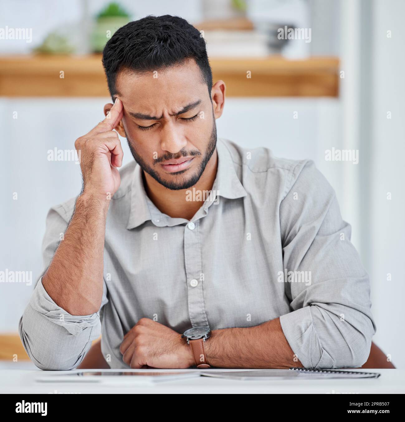 I desperately need a break. a young businessman experiencing a headache while at work. Stock Photo