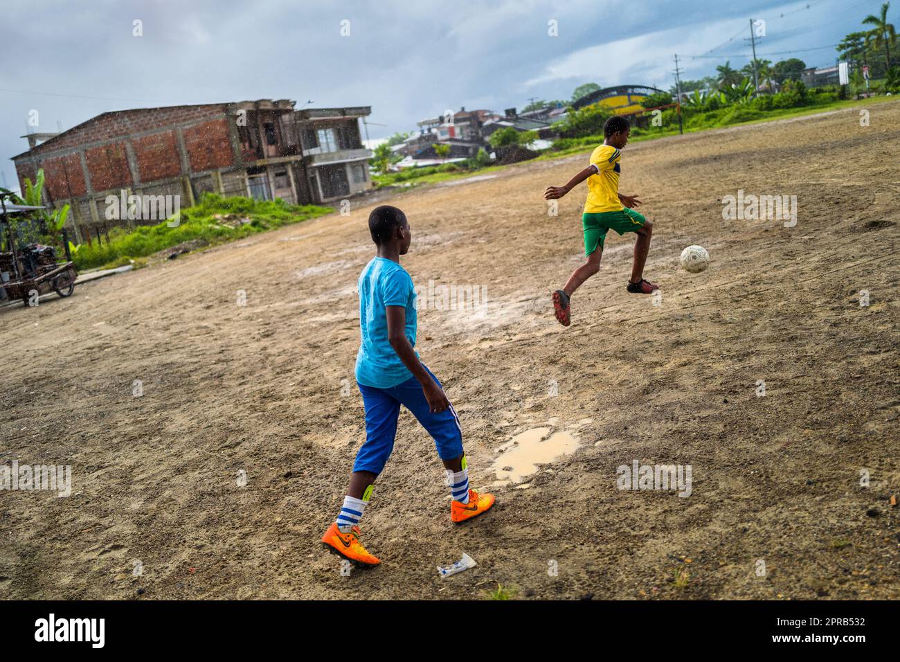 Afro-Colombian boys drill ball control during a football training session on a dirt playing field in Quibdó, Chocó, Colombia. Stock Photo