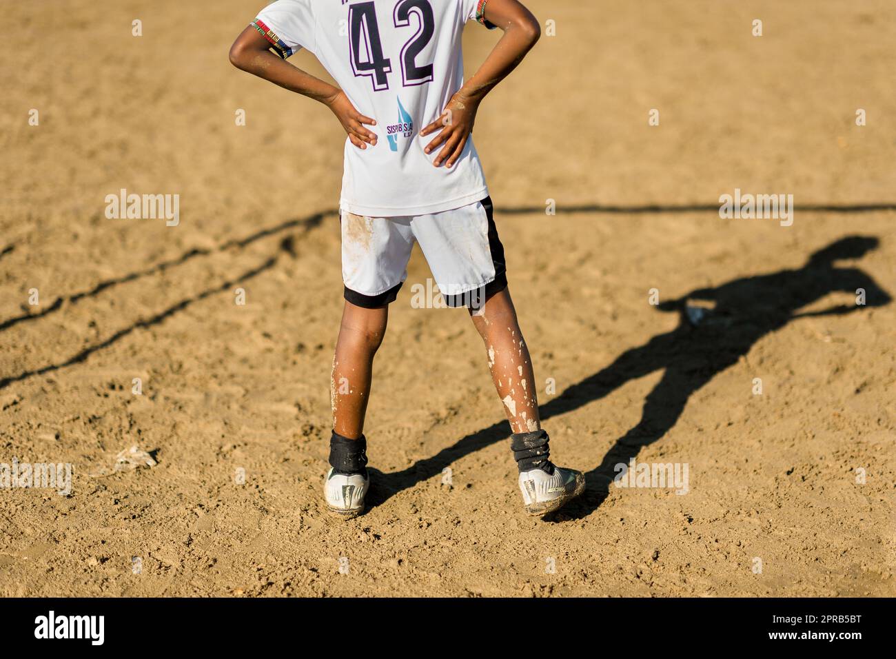 A young Afro-Colombian football player watches the game from the goal area during a training session in Necoclí, Antioquia, Colombia. Stock Photo