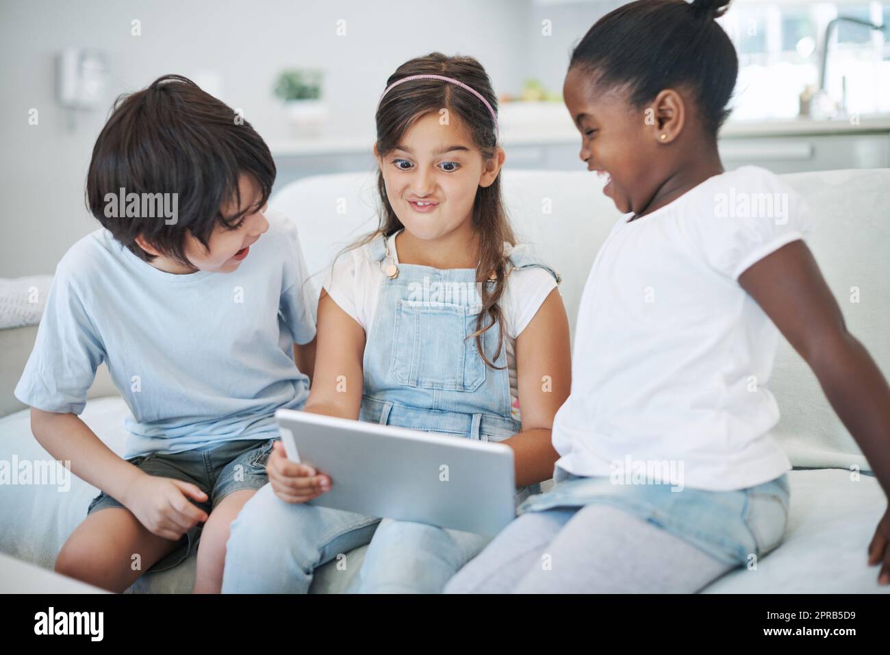 Im the class clown. a group of little children using a digital tablet at home. Stock Photo