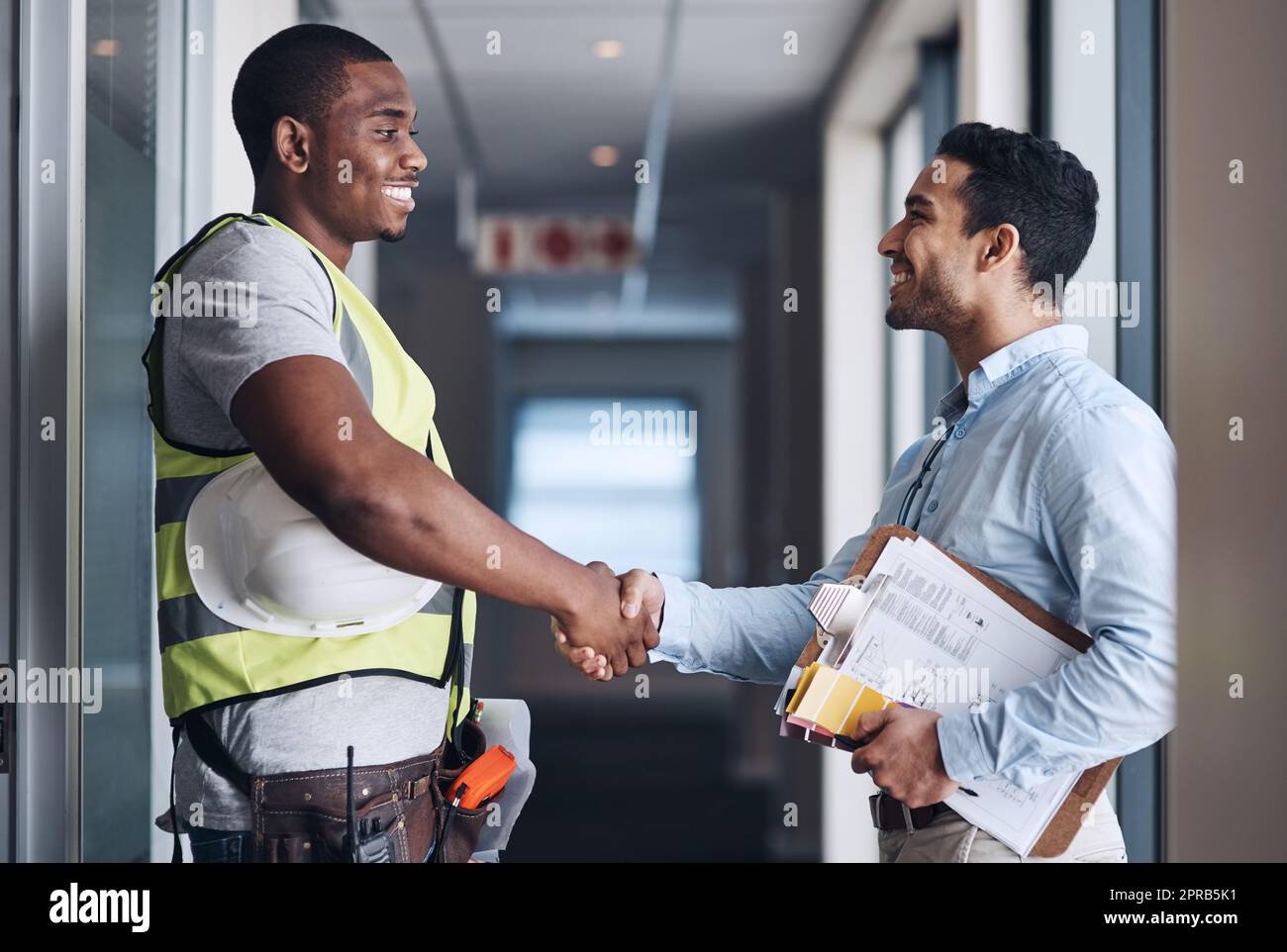 Thank you for trusting us with your renovations. two young architects standing together and shaking hands after a discussion about the room before they renovate. Stock Photo