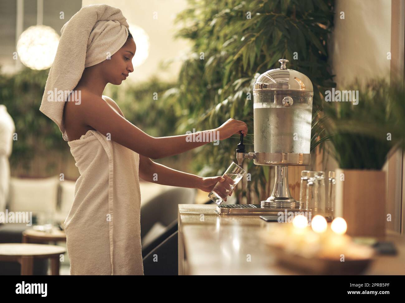 A spa day leaves me feeling lighter, brighter and more in control. a woman filling her glass at a water dispenser in a day spa. Stock Photo
