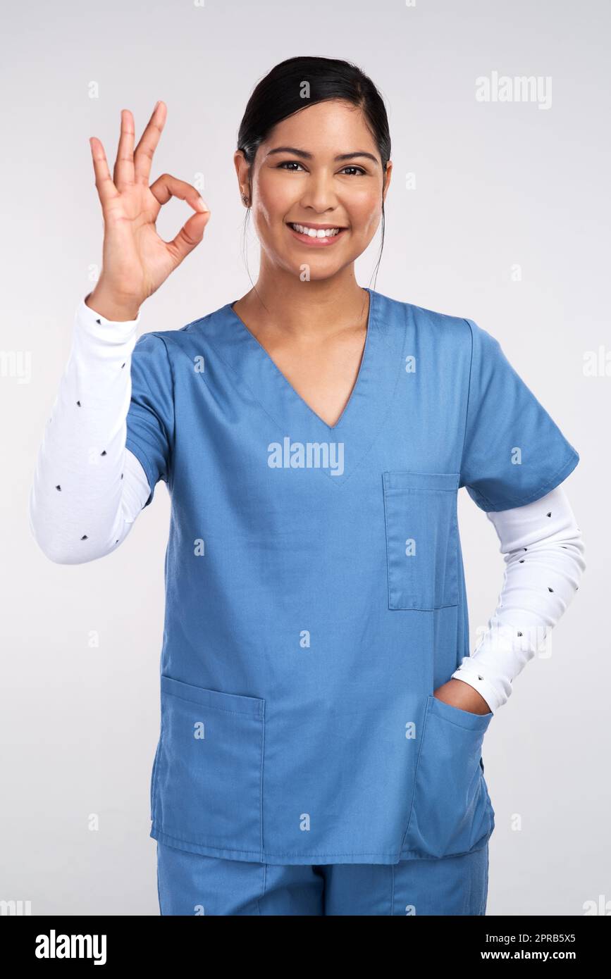 Deeper than the deepest of connections, ill travel inside you. Portrait of a young doctor showing the ok sign against a white background. Stock Photo