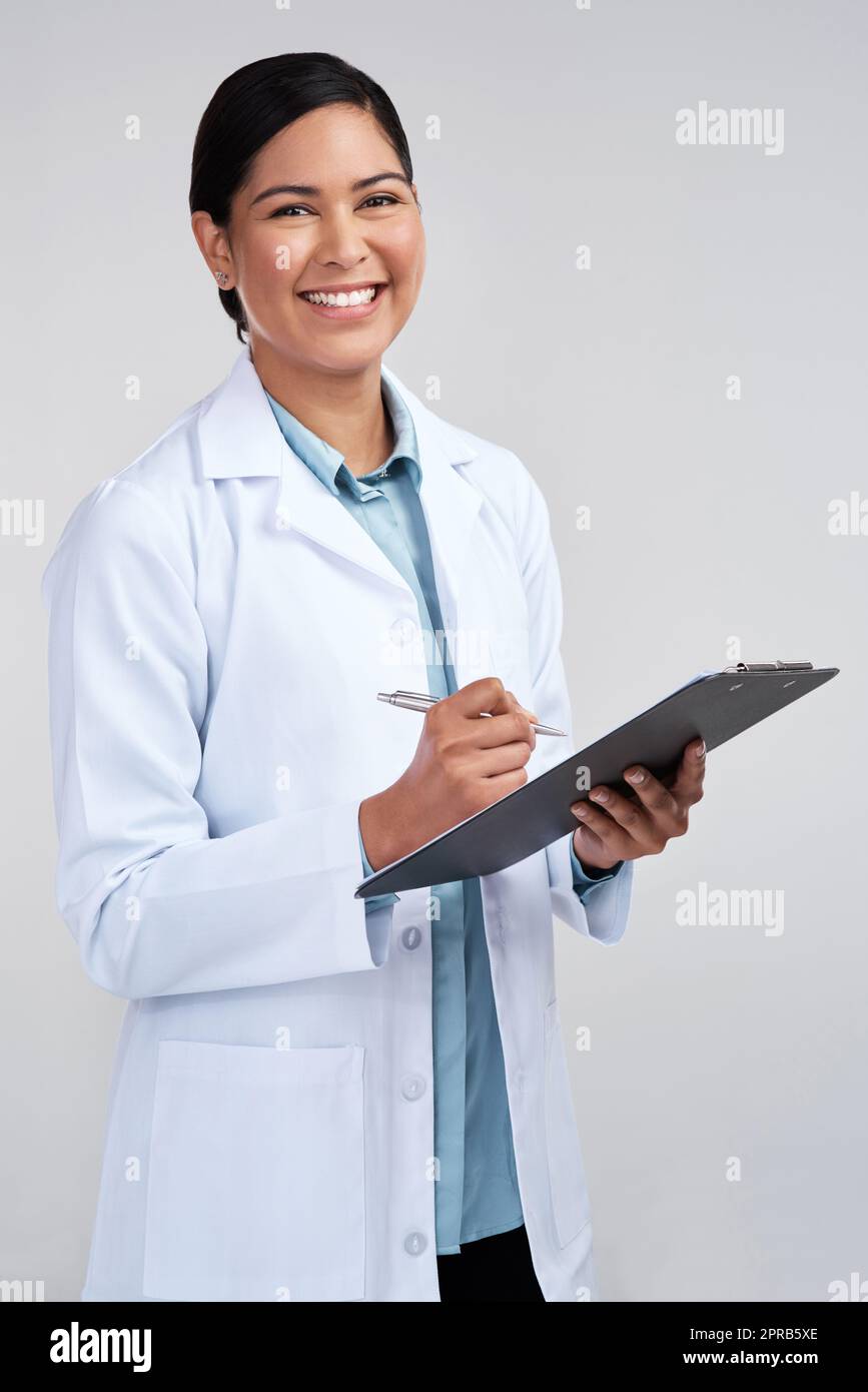 Documenting my findings. Cropped portrait of an attractive young female scientist working on a clipboard in studio against a grey background. Stock Photo