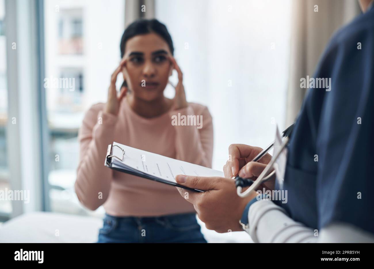 I have regular headaches. an unrecognizable doctor writing down a patients information in an office. Stock Photo