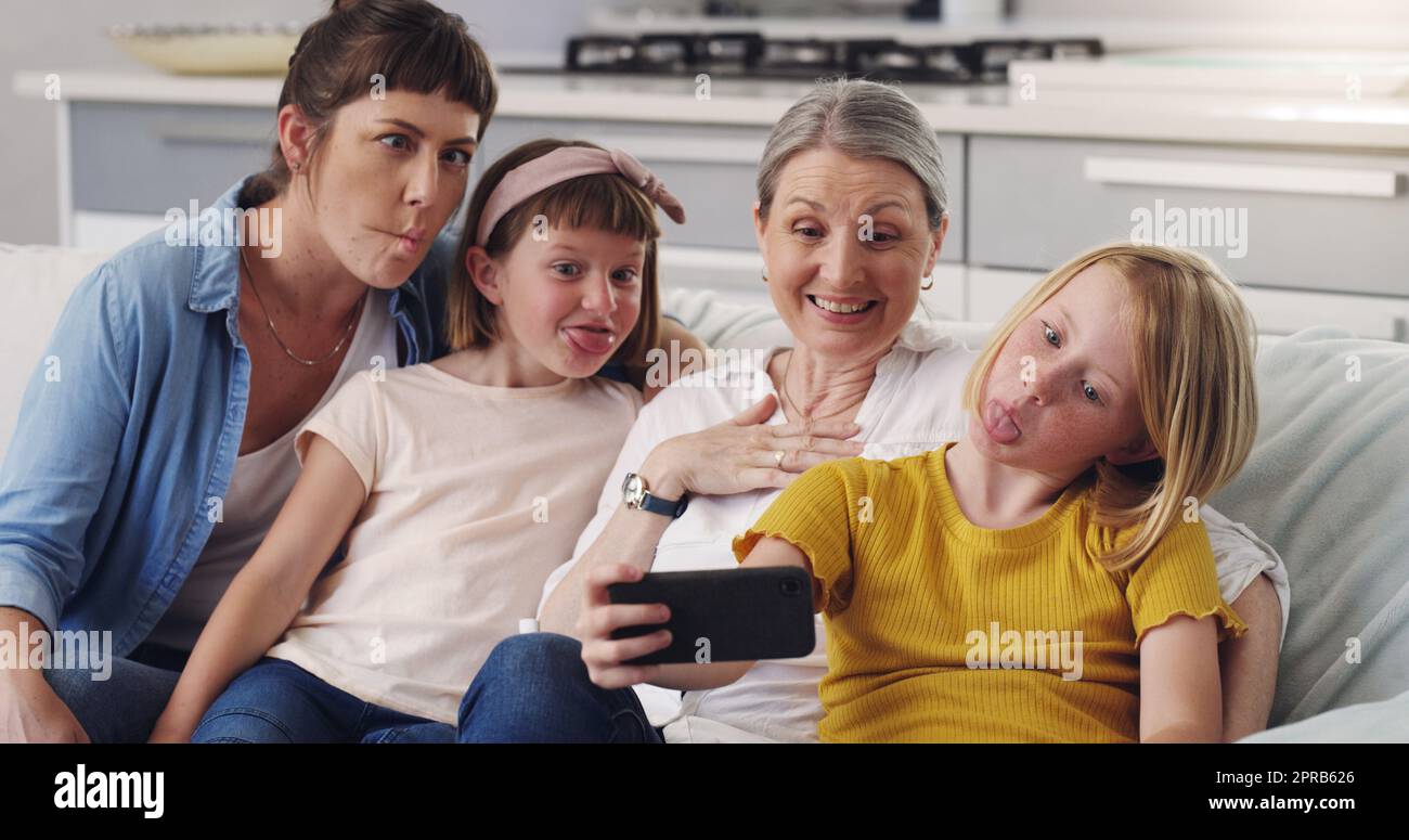 Now make a funny face. a grandmother taking a selfie with her daughter and granddaughters. Stock Photo