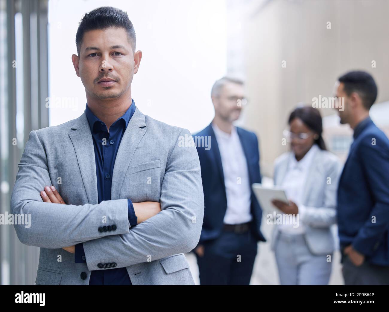 Face the day with confidence. Cropped portrait of a handsome mature businessman standing outside with his arms folded with his colleagues in the background. Stock Photo